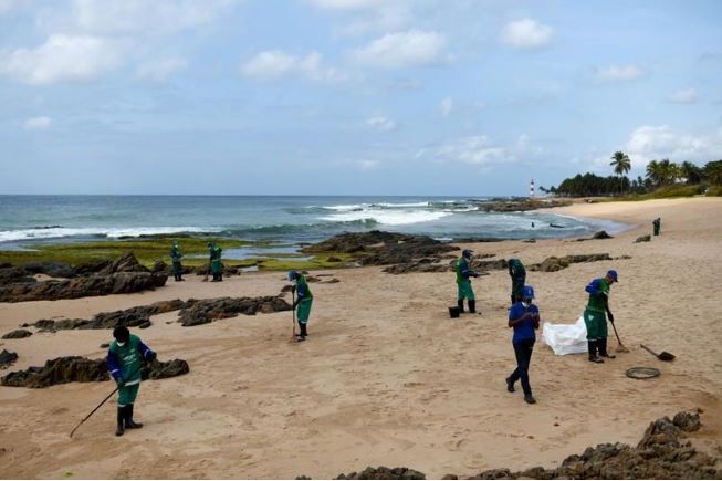 موظفون يشاركون في مهام إزالة بقعة نفطية على شاطئ بولاية باهيا في البرازيل يوم الأربعاء. تصوير. لوكاس لانداو - رويترز